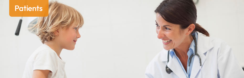 A female medical professional looking and smiling at a young blonde hair boy.
